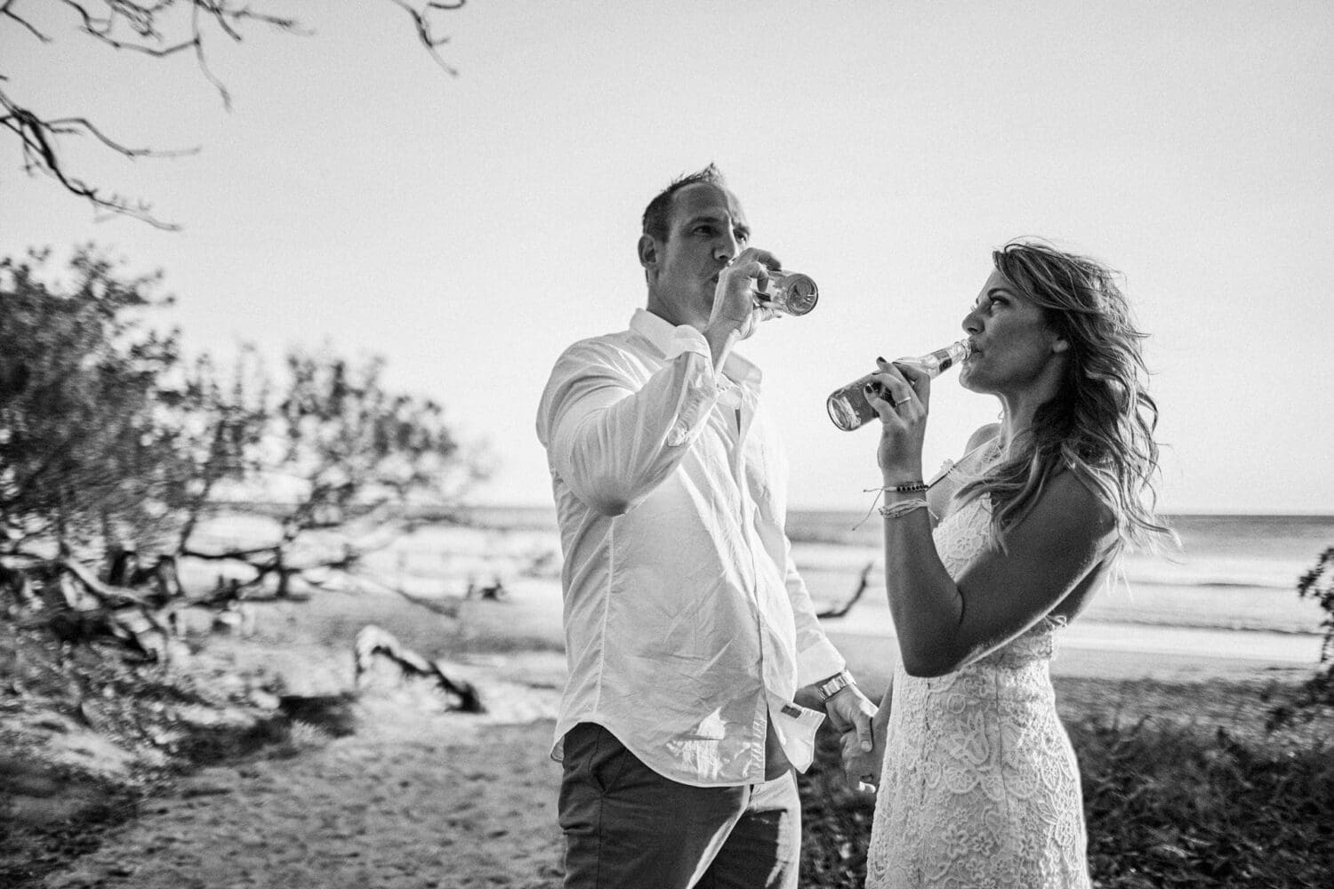 Bride and groom enjoying a quiet drink together on a tropical beach before sunset in Costa Rica.