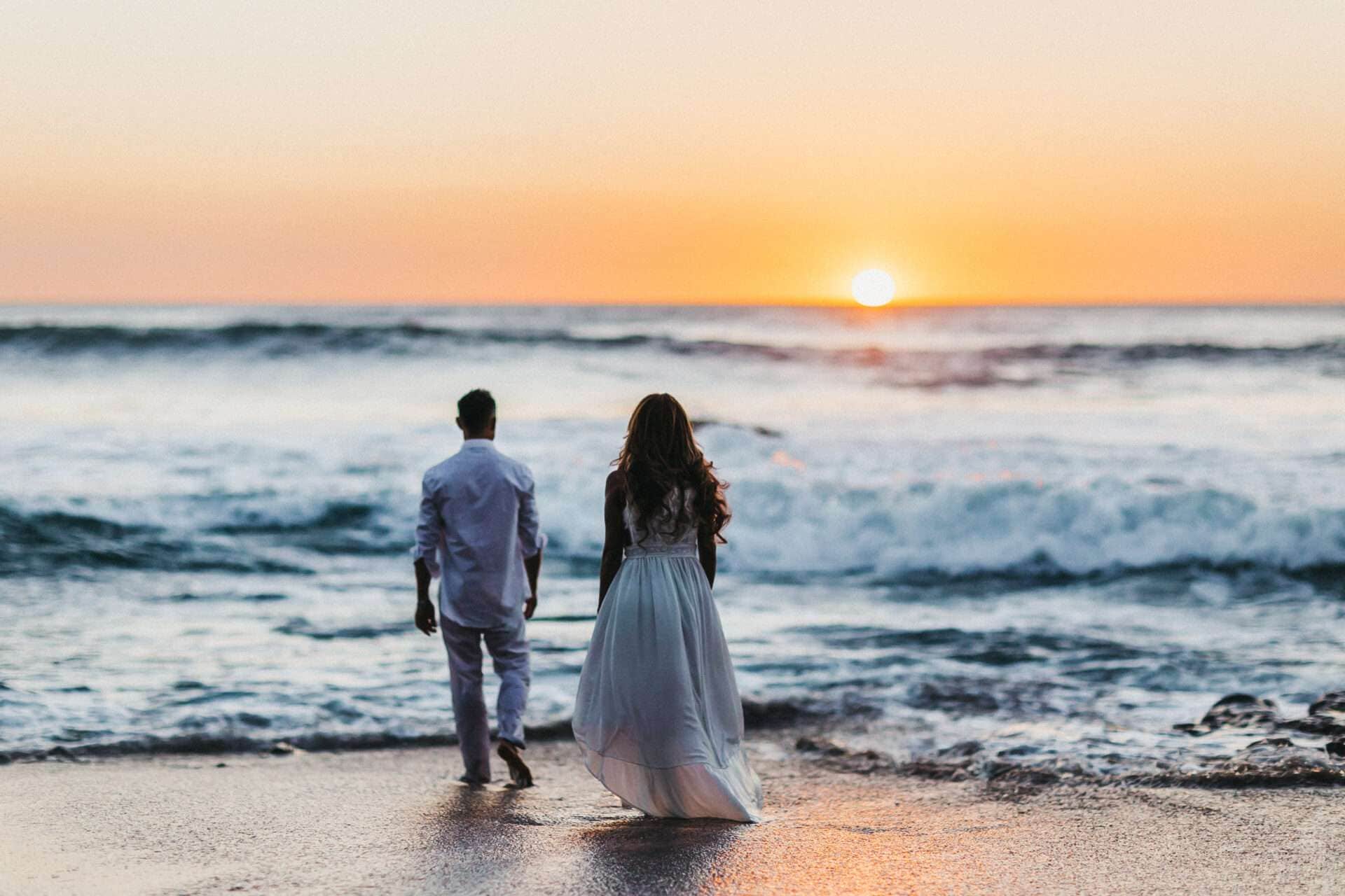 Bride and groom walking toward the ocean during sunset after their destination wedding in Costa Rica.