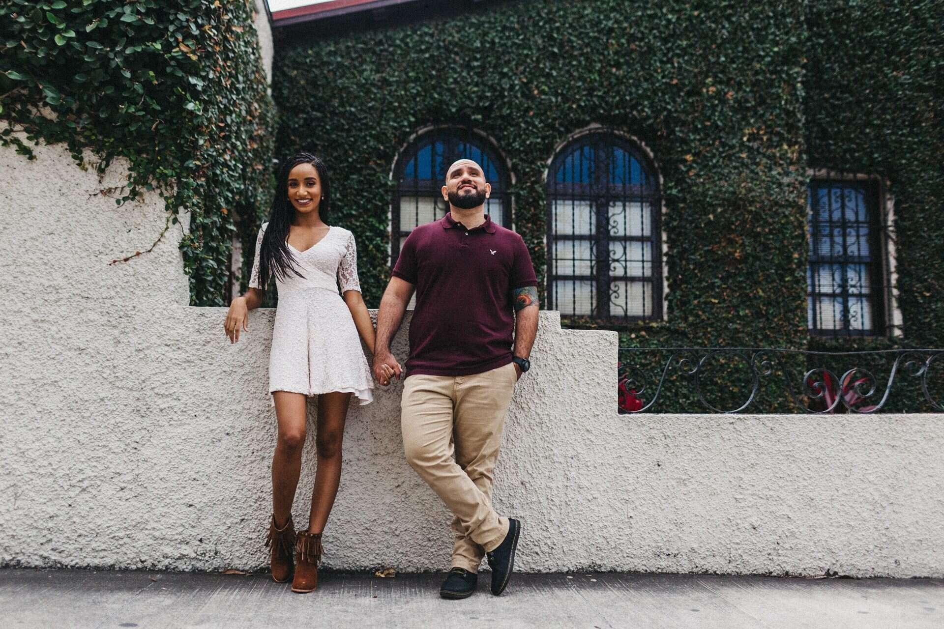 Couple posing in front of an old house in Costa Rica, blending cultural elements with their engagement session photography.