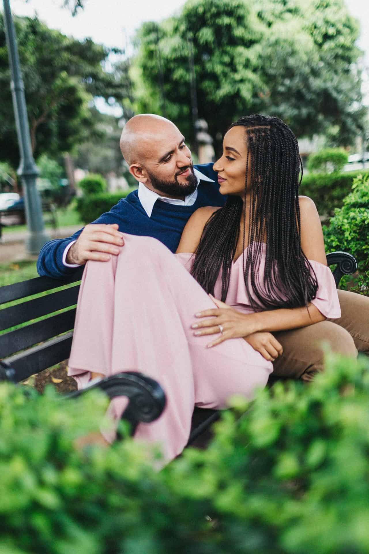 Couple sitting on a park bench in San José during their engagement session, framed by greenery and capturing a relaxed, romantic moment.