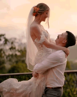 A groom lifting his bride at sunset, with jungle hills behind them